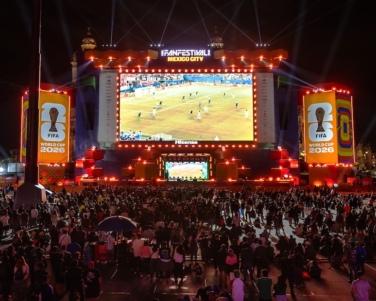 Nighttime view of the FIFA Fan Festival Mexico City main stage, spotlights sweeping the sky above the illuminated Hisense-branded screen, with a large crowd of fans gathered below.