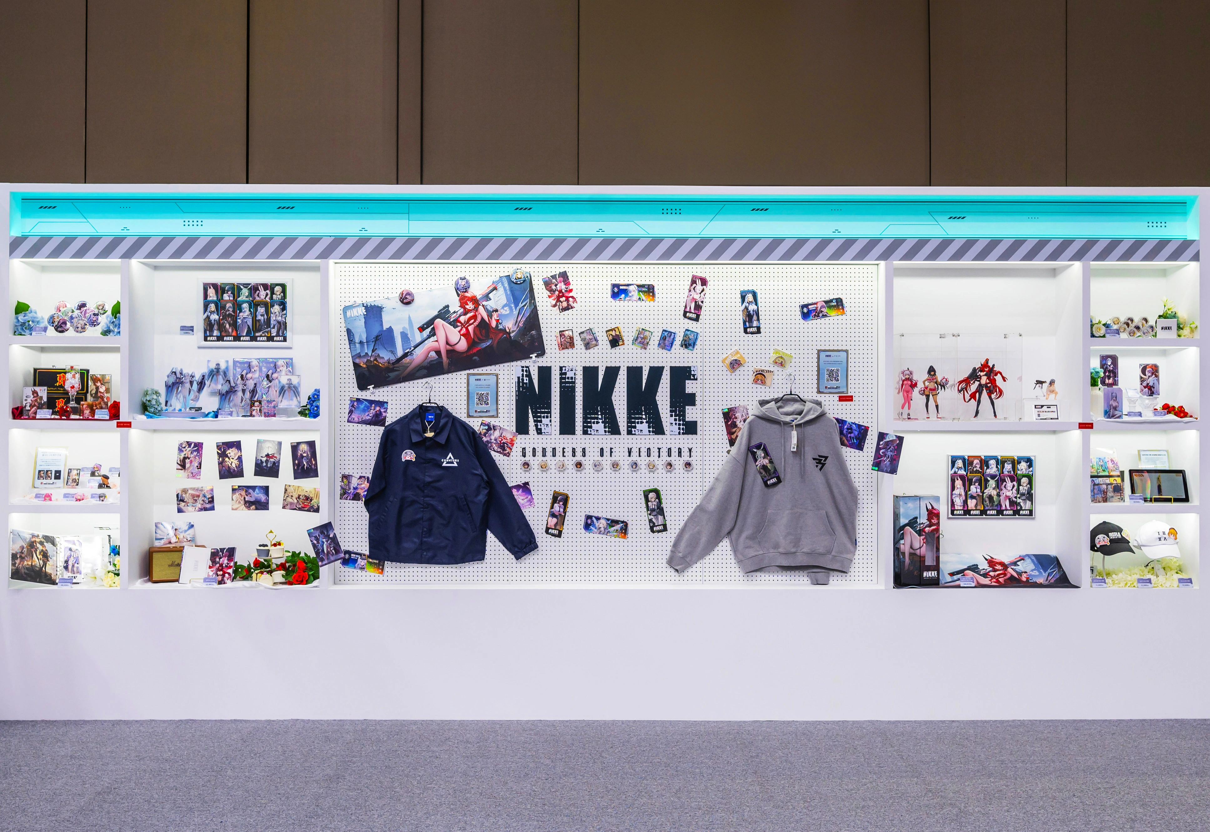 nikke merch zone show window at AGF: white background with mint colored light, centered NIKKE big signage and merch products on the wall